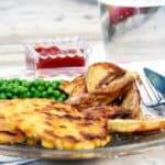 Vegan sweetcorn fritters, with peas, oven wedges and ketchup, on a glass plate