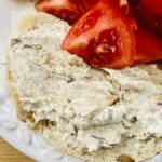 mackerel pate on a slice of sourdough on a white plate with quartered tomatoes