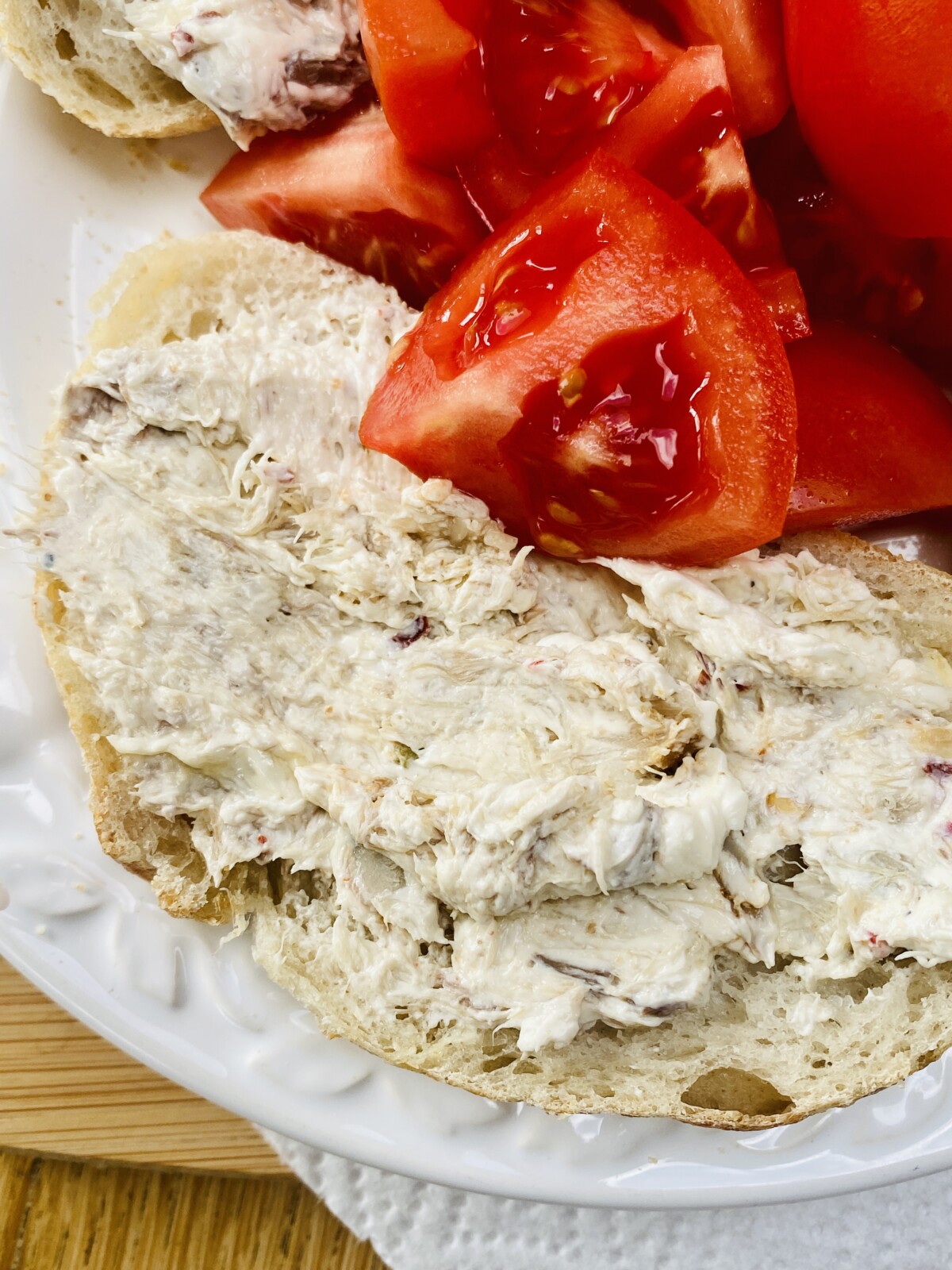mackerel pate on a slice of sourdough on a white plate with quartered tomatoes