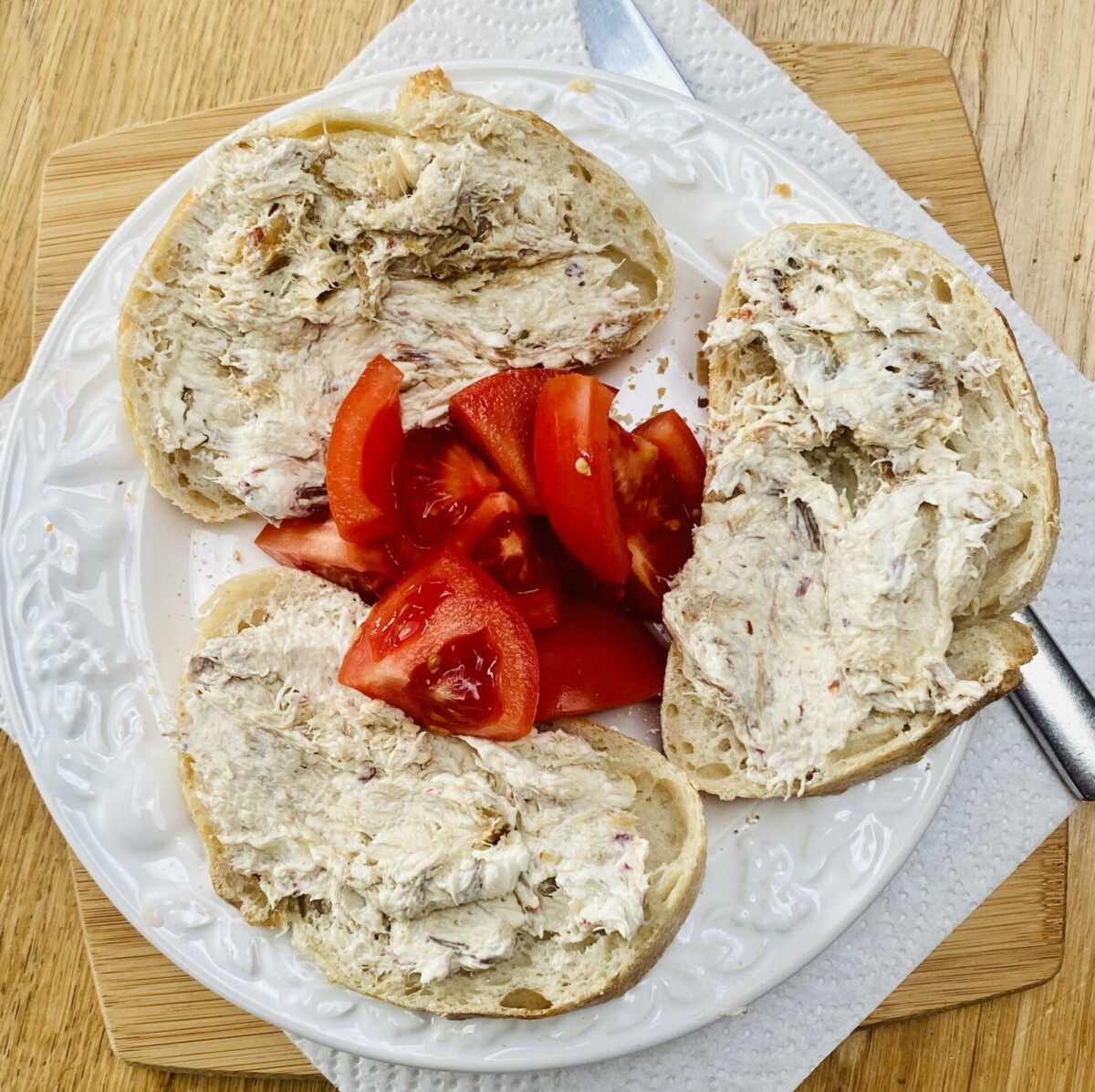 smoked mackerel pate on 3 small slices of sourdough, on a white plate, with quartered tomato