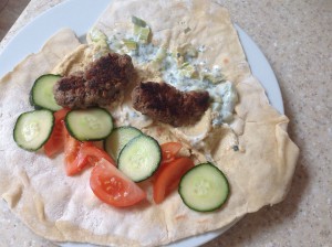 lamb kofta kebab on a home made flatbread with sliced tomato, cucumber and a relish