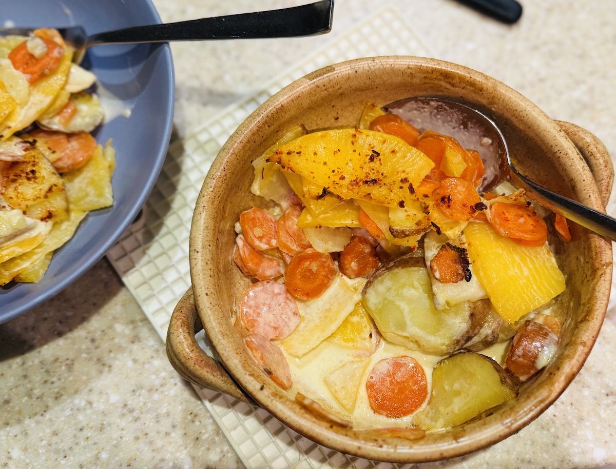 mixed vegetable dauphinoise in an earthenware dish.