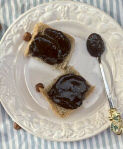 home made chocolate hazelnut spread on 2 small squares of bread, on a white plate, with a spoon
