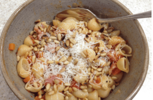 tomato bacon pasta in a brown dish with a spoon