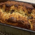 a close up picture of baked banana bread still min the loaf tin it was baked in.