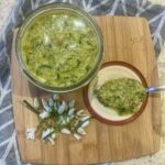 wild garlic pesto in a glass jar, on a wooden board, with a spoon