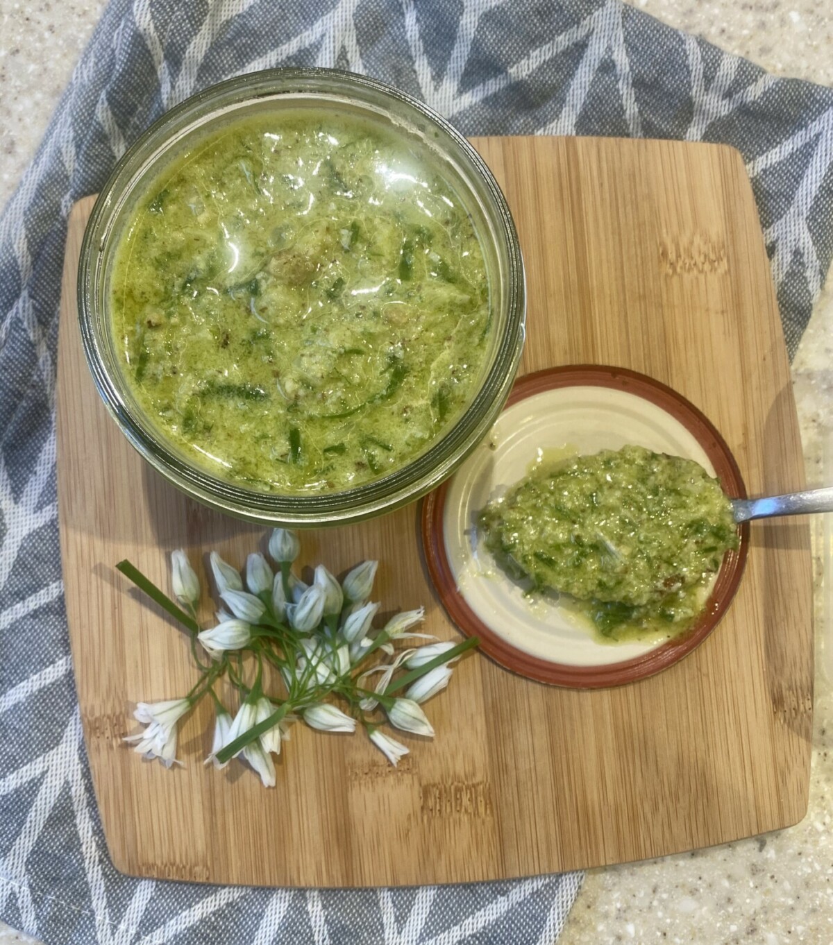 wild garlic pesto in a glass jar, on a wooden board, with a spoon