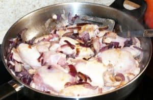 Chicken frying in a pan, with onions