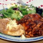 Honey and Soy chicken on a blue patterned plate with baked potato and sala