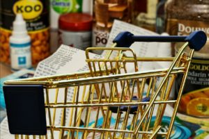 A shopping cart, with groceries in the background