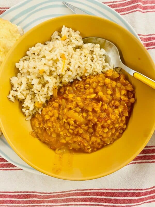 simple red lentil tomato dahl in a mustard coloured dish