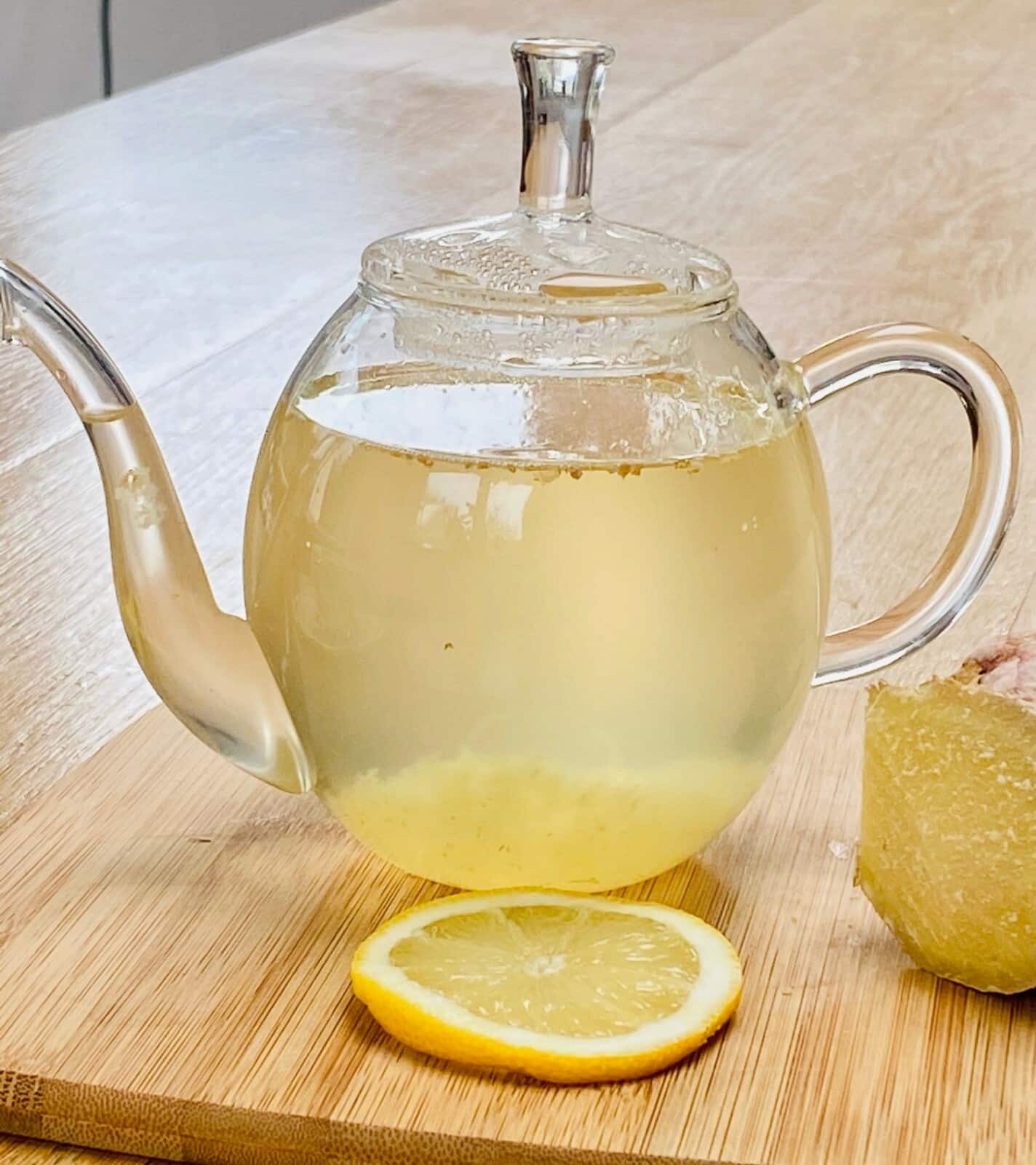 fresh ginger tea in a glass tea pot with a slice of lemon