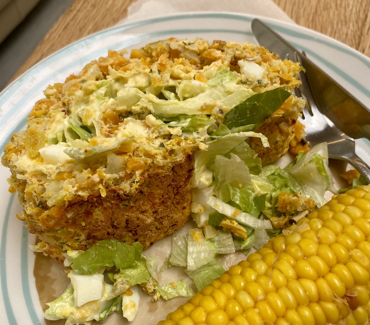 a slice of vegetable roulade on a plate with a corn cob.