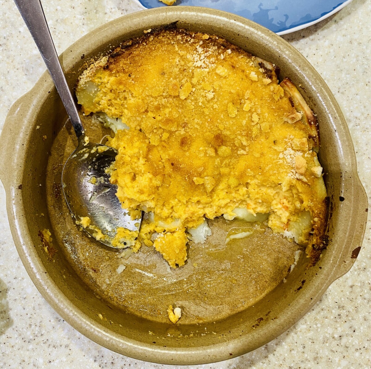 swede gratin in a beige pottery dish with a serving spoon