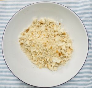 breadcrumbs in a white dish on a blue striped tea towel.