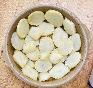 a pottery dish lined with cooked potato slices