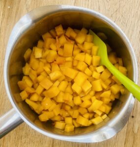 a stainless steel saucepan containing cooked cubes of swede.