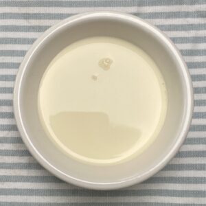 double cream in a white dish on a blue striped tea towel.