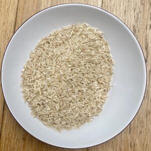 uncooked brown rice in a white bowl.