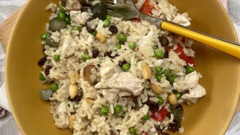 brown rice and chicken salad in a mustard coloured flat profile bowl, with a mustard coloured handle fork in one side.