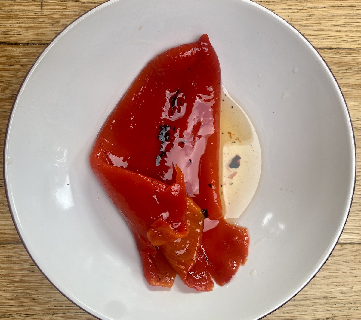 a roasted red pepper from a jar in a white bowl.