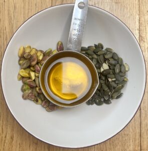 pistachios, pumpkin seeds and cold pressed rapeseed oil in a white bowl.