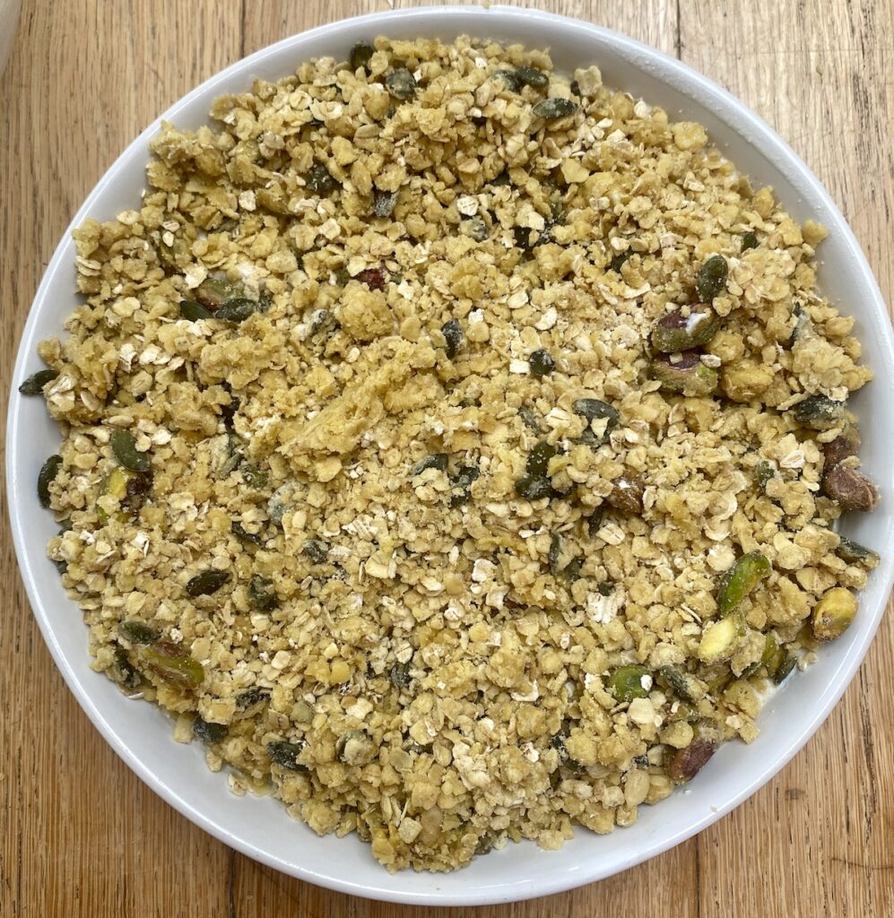 uncooked chicken and mushroom crumble, in a white dish.