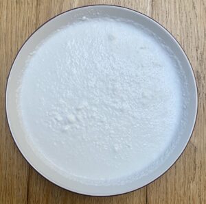 Coconut milk powder, rehydrated, in a white bowl.