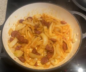 chorizo and onion being sautéed in a black cast iron pot.
