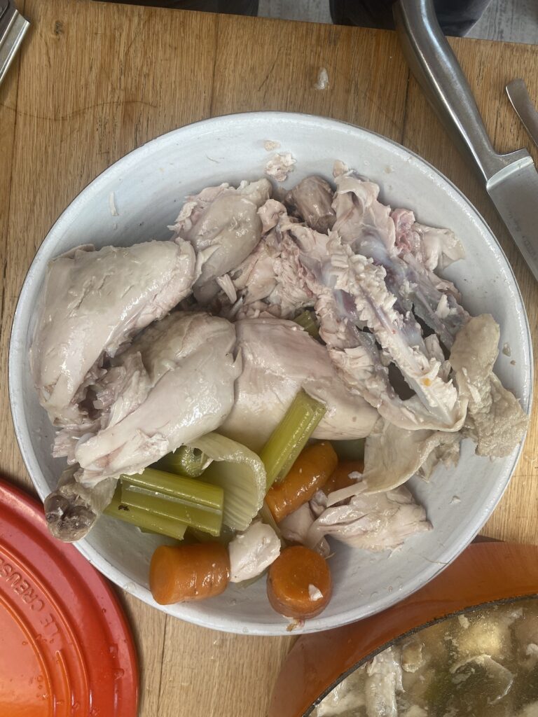 poached chicken in a white dish stripped from the bones. 