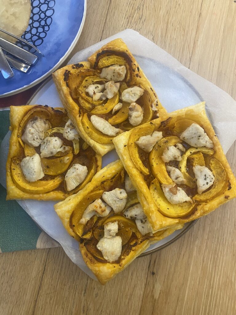 Baked puff pastry squares with red pesto, butternut squash and chicken on a plate. 