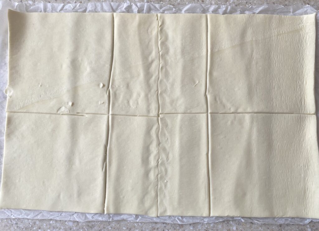 A sheet of puff pastry cut into 6 squares.
