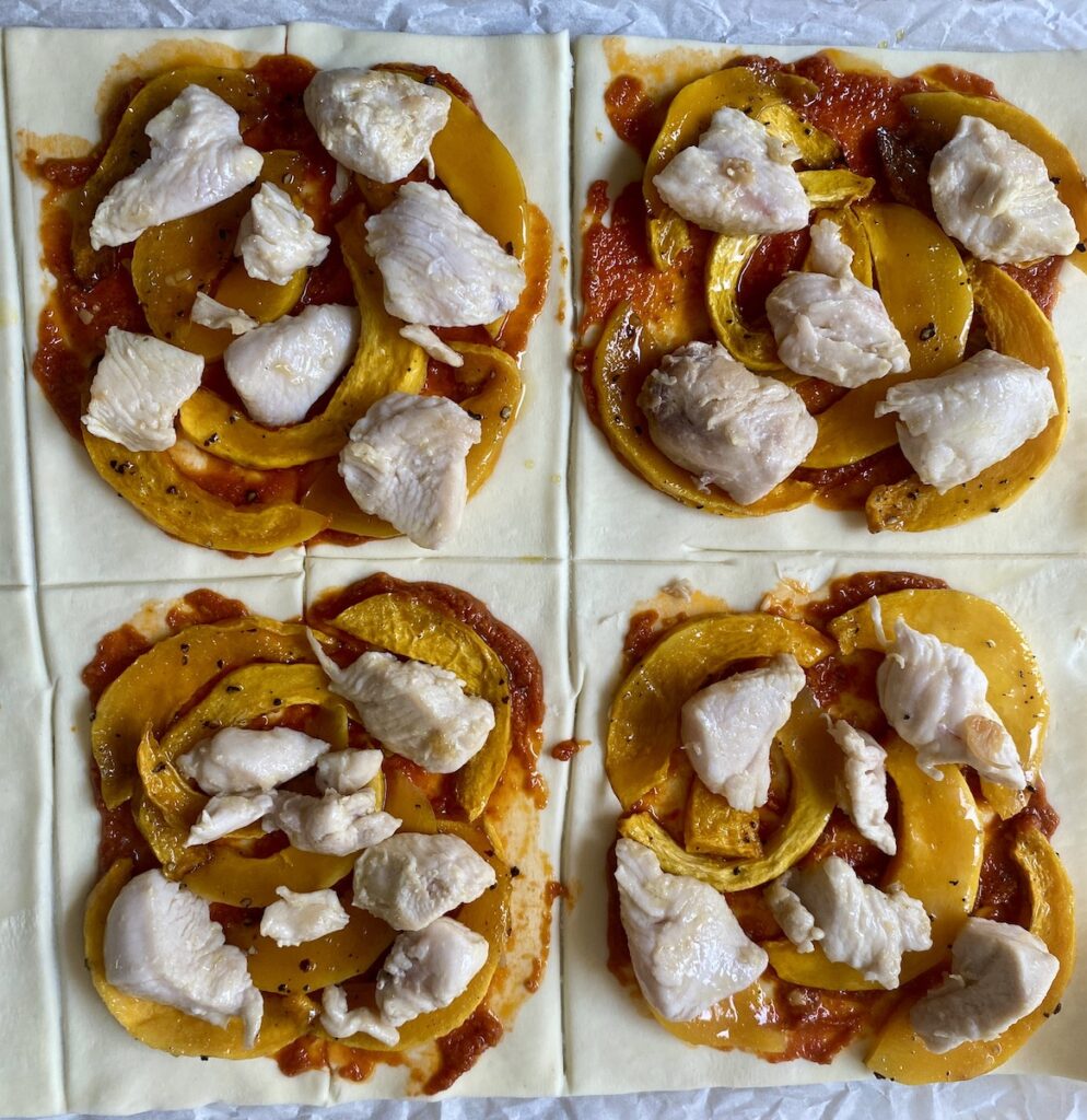 Puff pastry squares with red pesto, butternut squash and chicken. Not yet cooked.