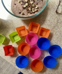 empty coloured silicone cases wit a bowl of muffin mixture nearby.
