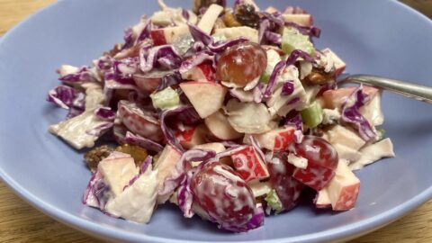 Red cabbage and chicken waldorf salad in a blue bowl.