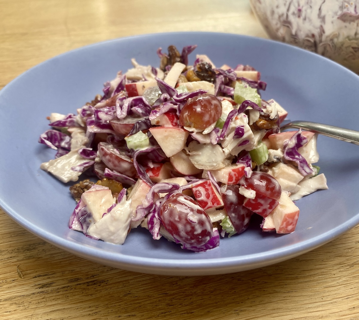 Red cabbage and chicken waldorf salad in a blue bowl.