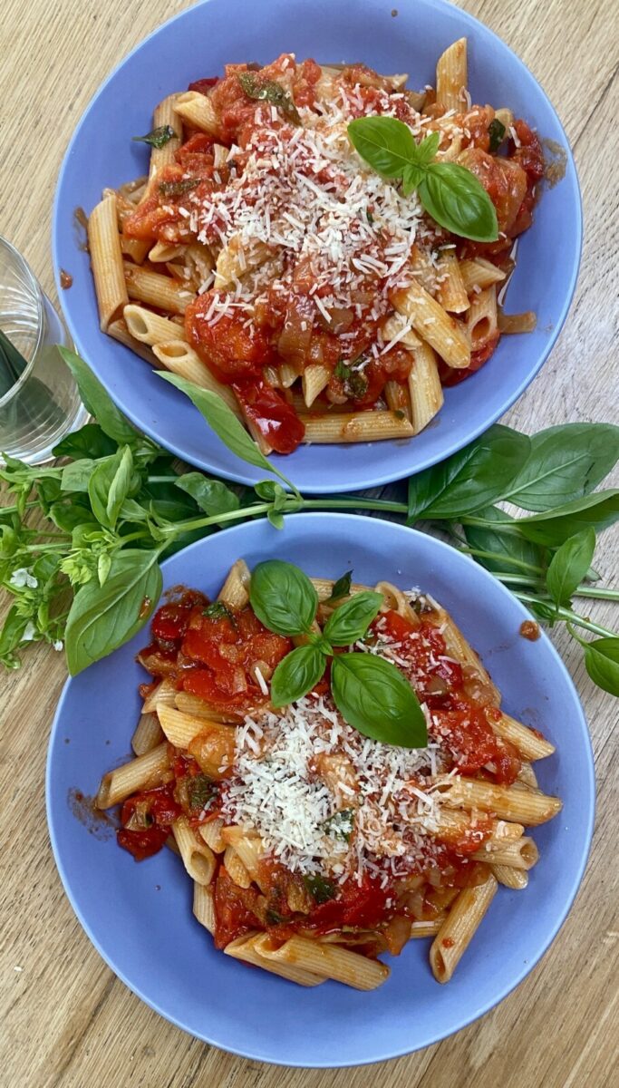 2 blue bowls filled with pasta con peperonata. 