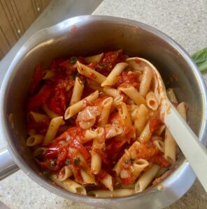 cooked pasta mixed with peperonata in a metal saucepan.