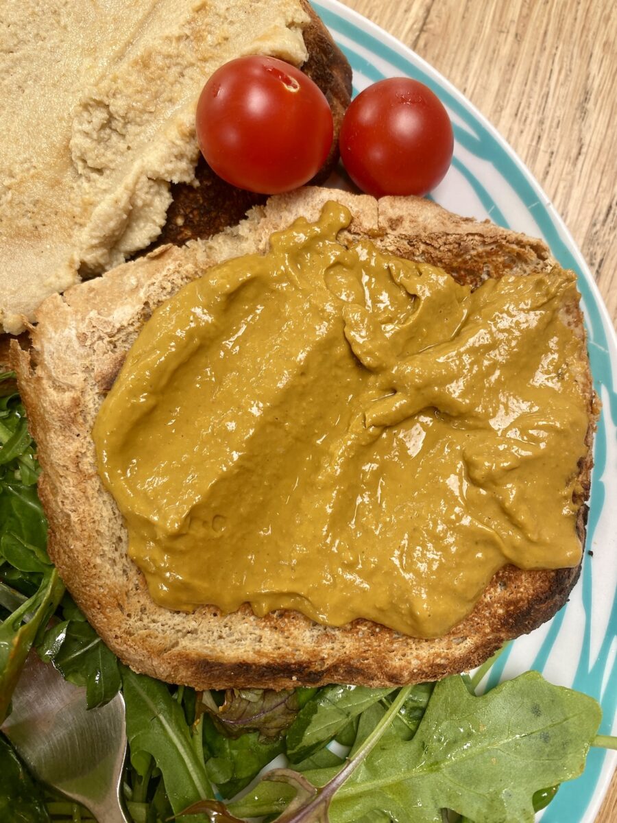 tomato curd on wholemeal toast, on a blue striped plate, with dressed leaves.