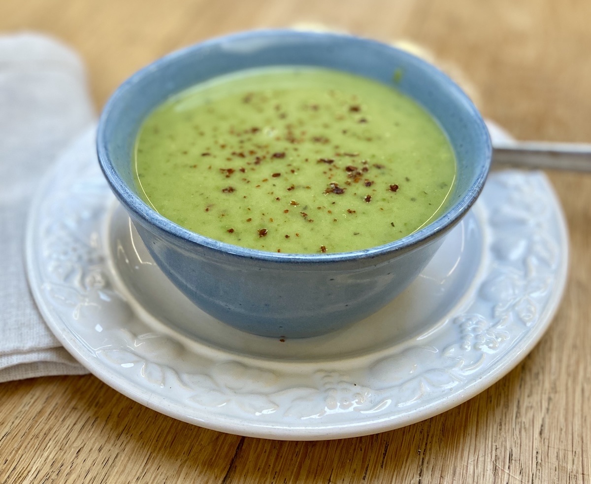 green pea soup in a blue bowl on a white plate. 