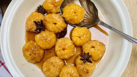 A cream coloured dish of spiced clementines.