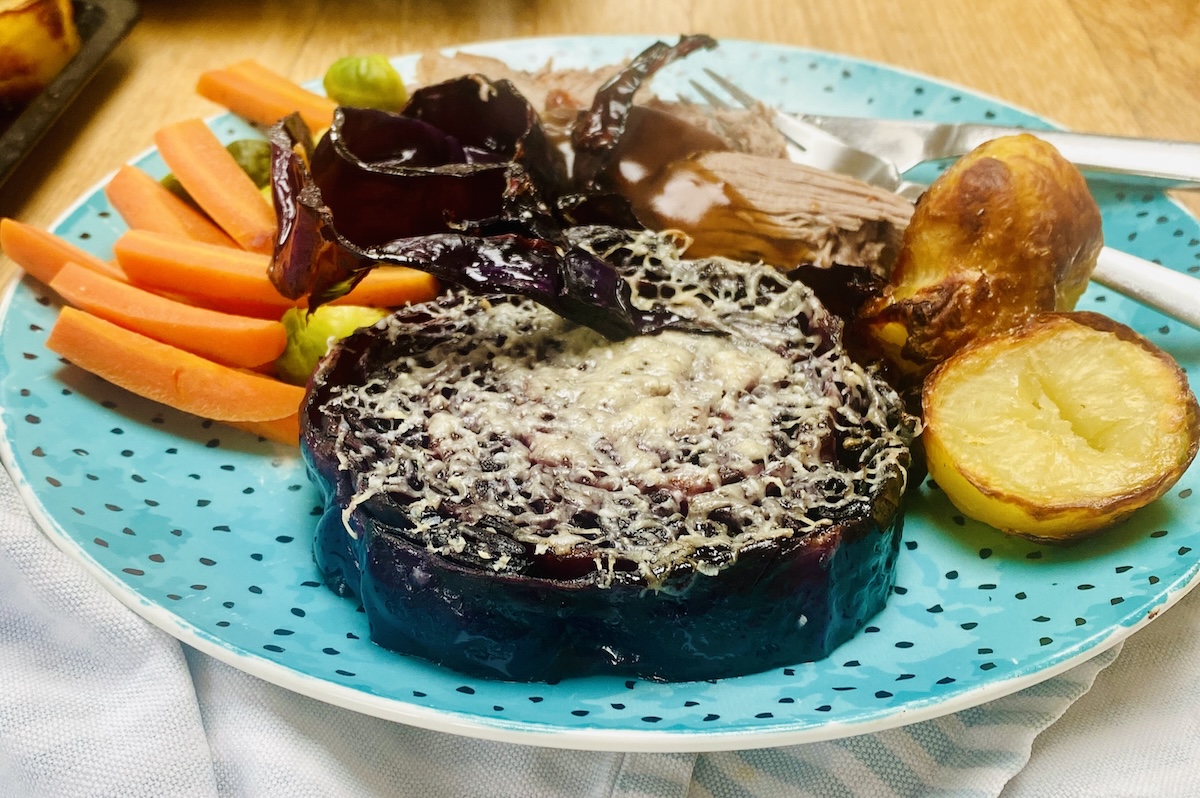 a plate of dinner with red cabbage steaks. 