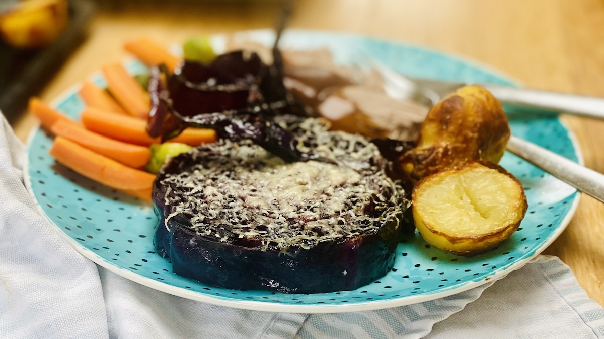 a plate of dinner showing roasted red cabbage steaks in foreground.