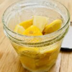 A jam jar with lemons cut into small pieces and covered with salt.