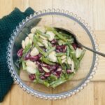 3 bean salad in a glass bowl with glass bobbles all round the rim, with a spoon.