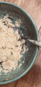 a close up view of a cheese and onion sandwich filling, in a duck egg blue bowl, with a spoon.