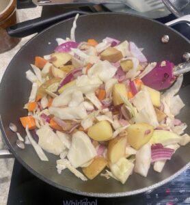 various vegetables cooking in a large pan.