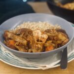 leftover chicken curry, in a blue bowl, on a blue striped plate.
