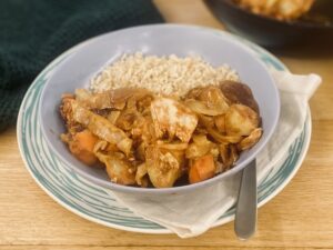 leftover turkey curry in a blue bowl, on a blue striped plate.