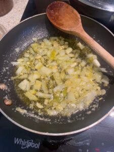 onion and garlic sizzling a small frying pan.